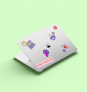 Semi-open laptop with Angie Contreras branding stickers on the cover, placed on a green background.