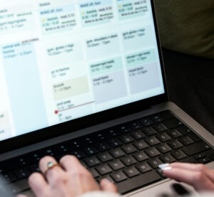 Woman’s hands typing on a laptop with a calendar view from ClientCare’s EHR system.