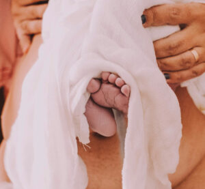 Midwife’s hands holding a newborn, representing ClientCare’s mission to focus on care, not paperwork.