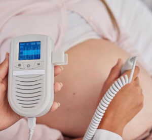 Midwife monitoring a pregnant woman’s belly, showcasing ClientCare’s prenatal care solutions.