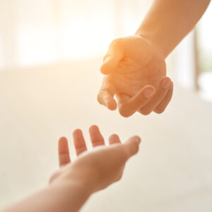 Hands offering help on a light, hopeful background.