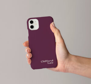 Wine-colored phone case featuring Clifford Lee’s logo, held by a woman’s hand.