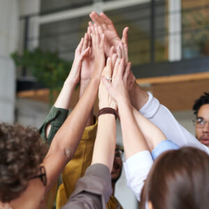 Six young hands high-fiving, symbolizing teamwork and collaboration.