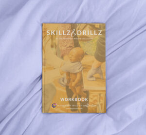 Closed Skillz&Drillz workbook with a yellow cover on purple fabric.