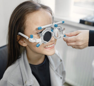 Smiling young girl taking an eye exam, reinforcing the importance of pediatric vision care.