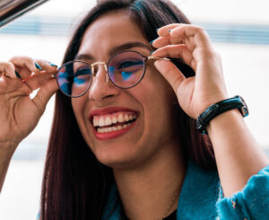 Young woman adjusting her glasses with both hands.