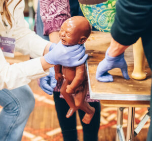 Midwife holding a newborn mannequin during a hands-on training session.