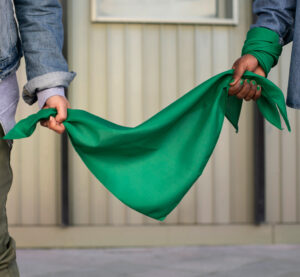 Two women holding a green scarf as a symbol of solidarity in the feminist fight for abortion rights.