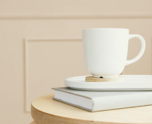 A gray book with a white ceramic cup and plate on a wooden surface, creating a minimalist decor look.