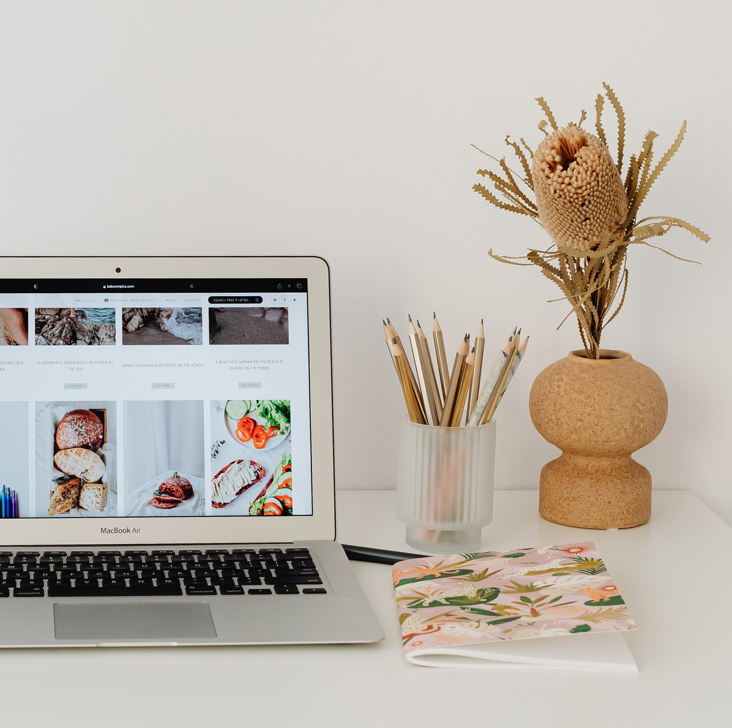 worldwide branding services Desk with a laptop displaying a website, surrounded by a notebook, pencils, and a vase, highlighting adamanto’s web design services.