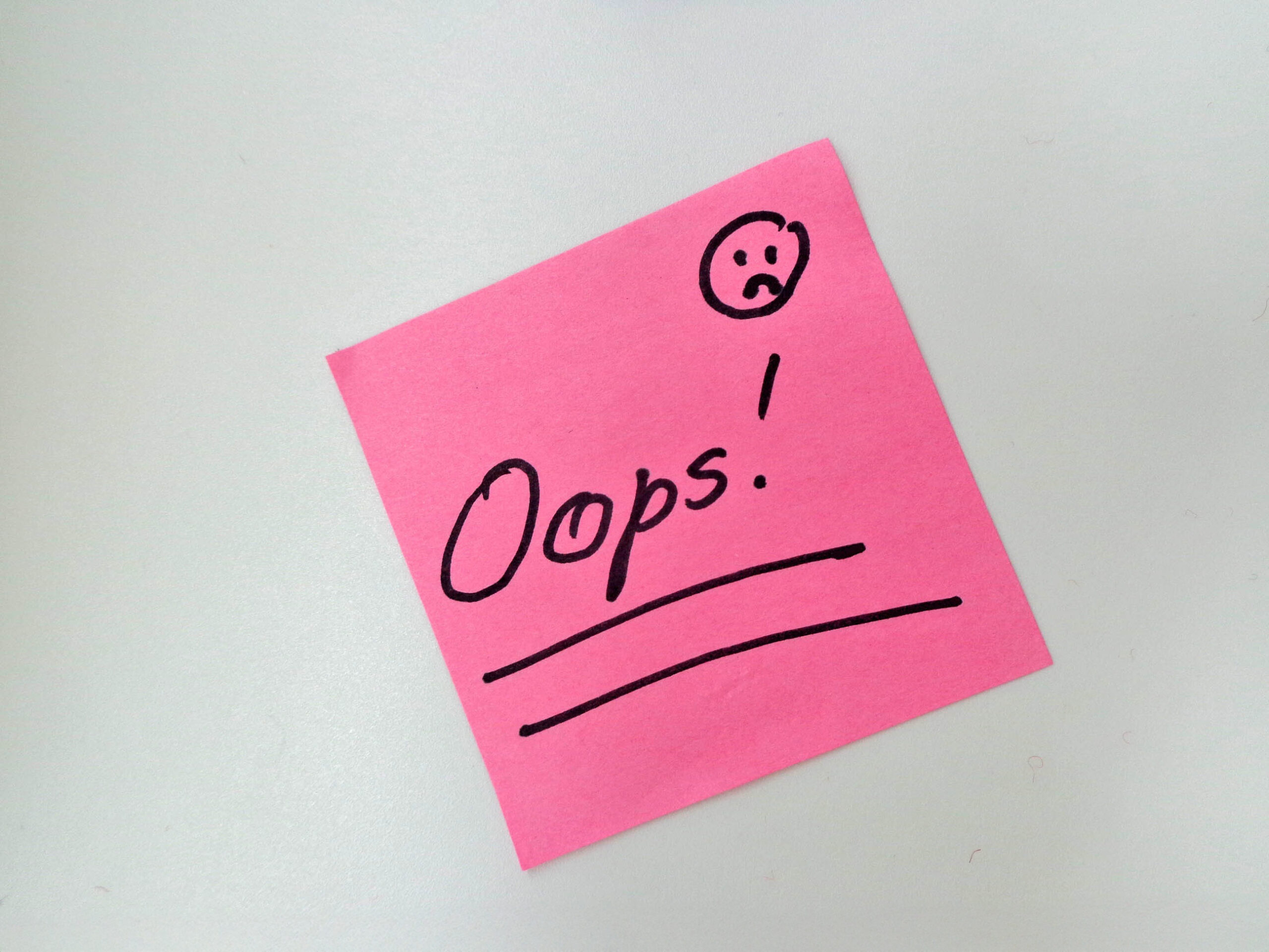 Post-it note with handwritten “oops!” and a sad face, representing branding mistakes.