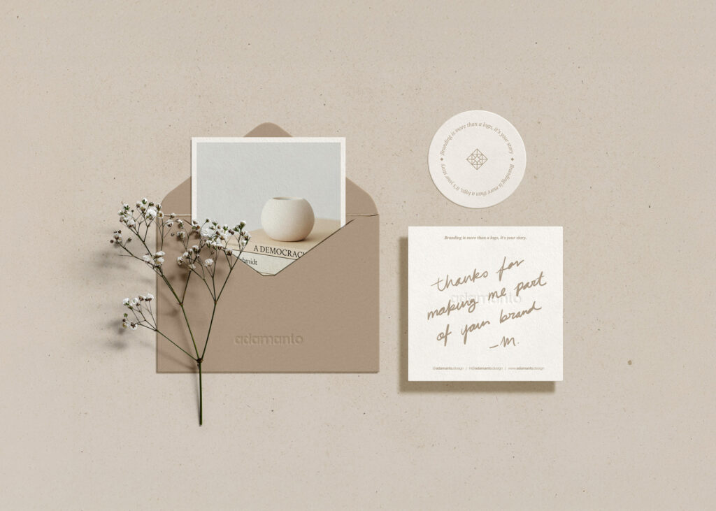 Branded envelope, custom notepad, sticker, and photo displayed in a beige-toned flat-lay.