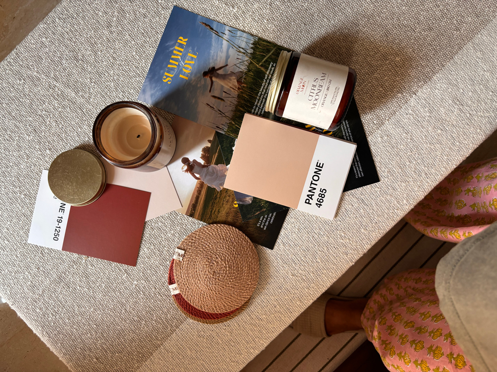 Warm-toned moodboard with Pantone cards, amber jars, and magazine clippings illustrating how to build a brand without a designer.