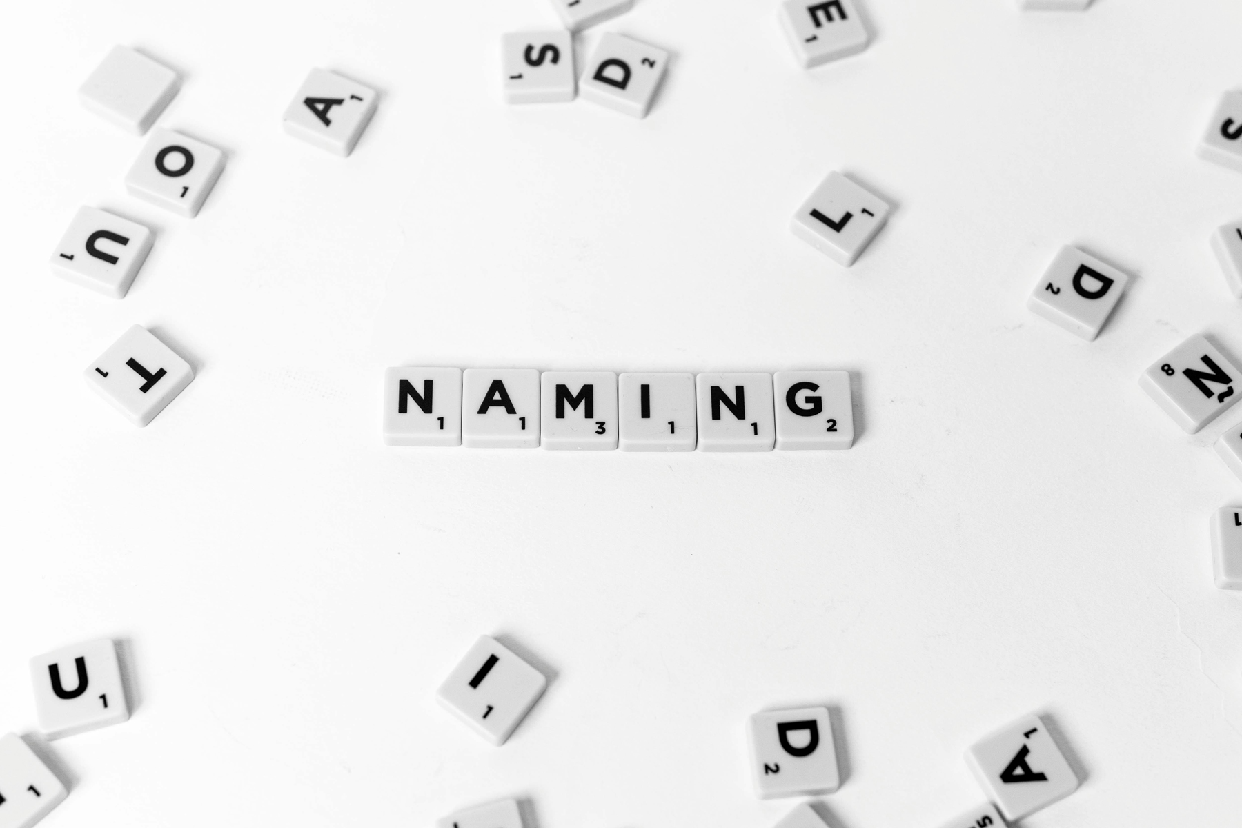 Letter tiles spelling “NAMING” on a white background, representing how to validate a business name before committing.