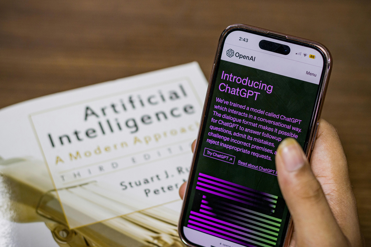 Smartphone displaying ChatGPT page with AI book in background illustrating the question: can AI design my logo for a business.