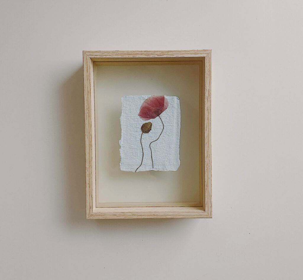 Pressed flower displayed in a wooden frame as part of the creative inspiration behind adamanto.