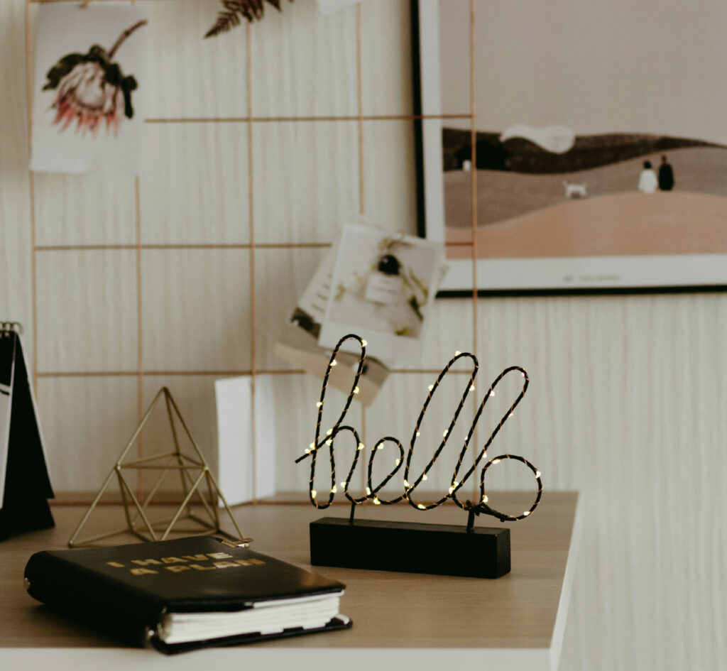Creative workspace of brand identity designer Monserrat Urueña featuring inspiration boards, sketchbooks, and a illuminated "hello" sign.